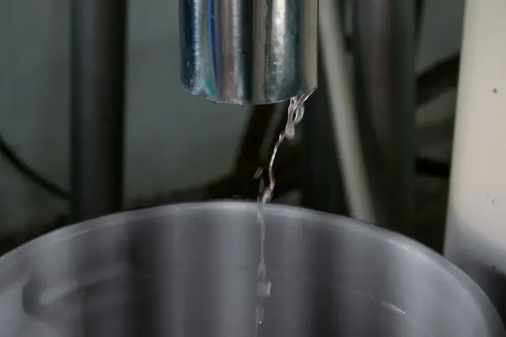 Crystal-clear virgin coconut oil flowing from the outlet